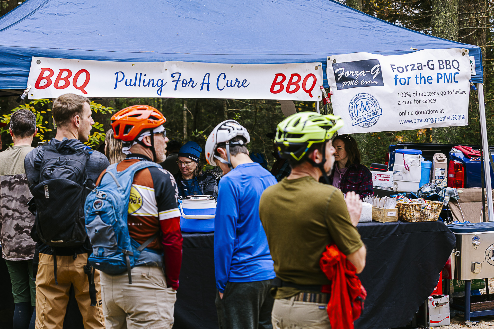 Riders line up at the Pulling For A Cure barbecue tent, which raises money for cancer research through the PMC