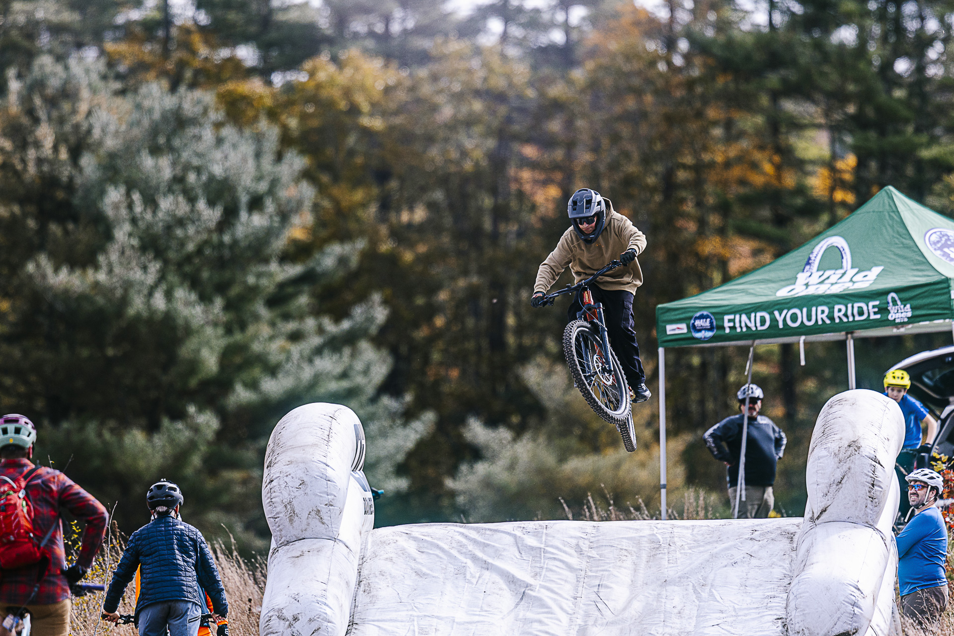A rider launches off a jump in the skills area while others watch