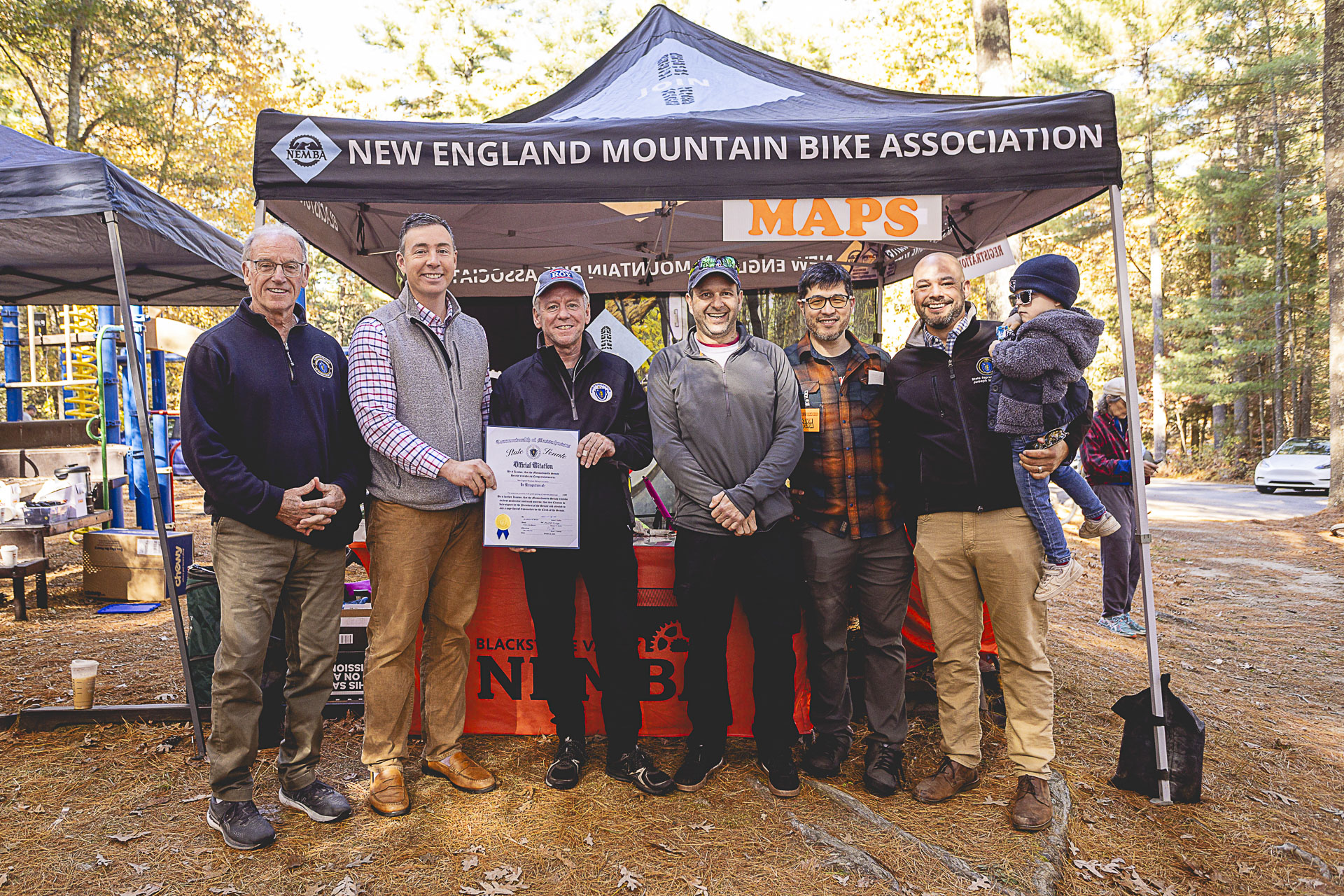 Chapter members and guests hold a certificate under the New England Mountain Bike Association tent