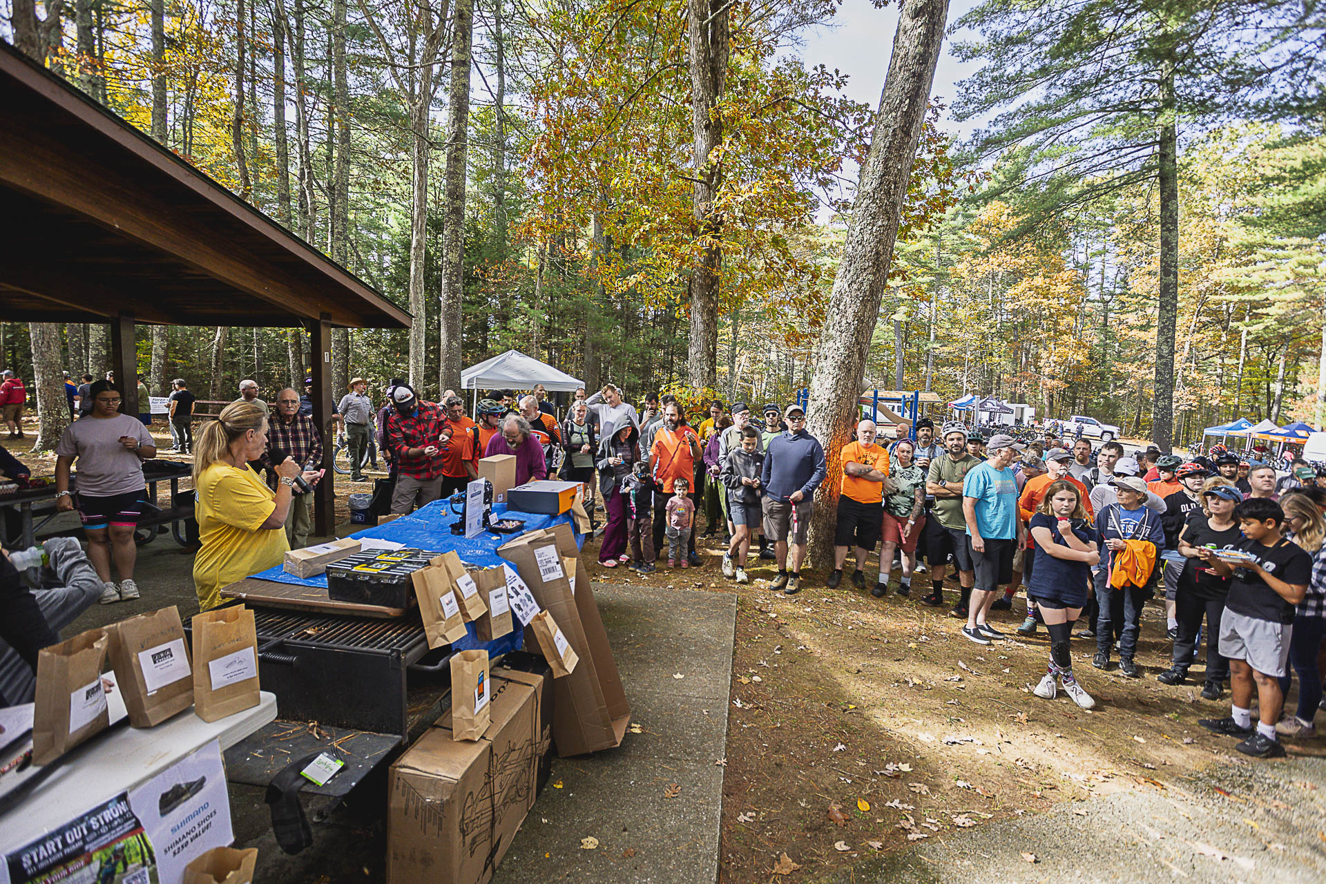 A large crowd gathers at the pavilion for the raffle, prize bags lined up on the tables