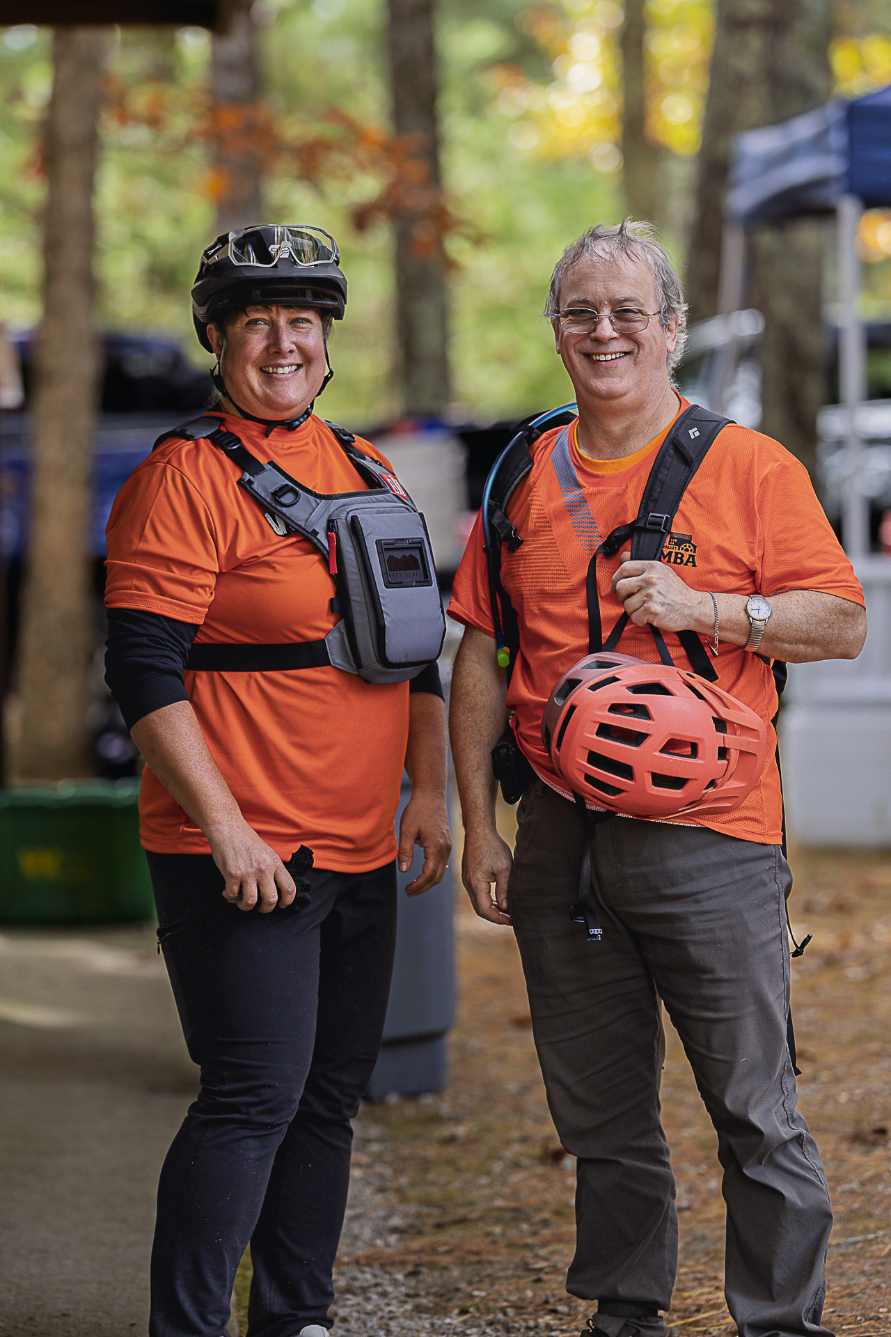 Two volunteers in orange shirts smile in the event area