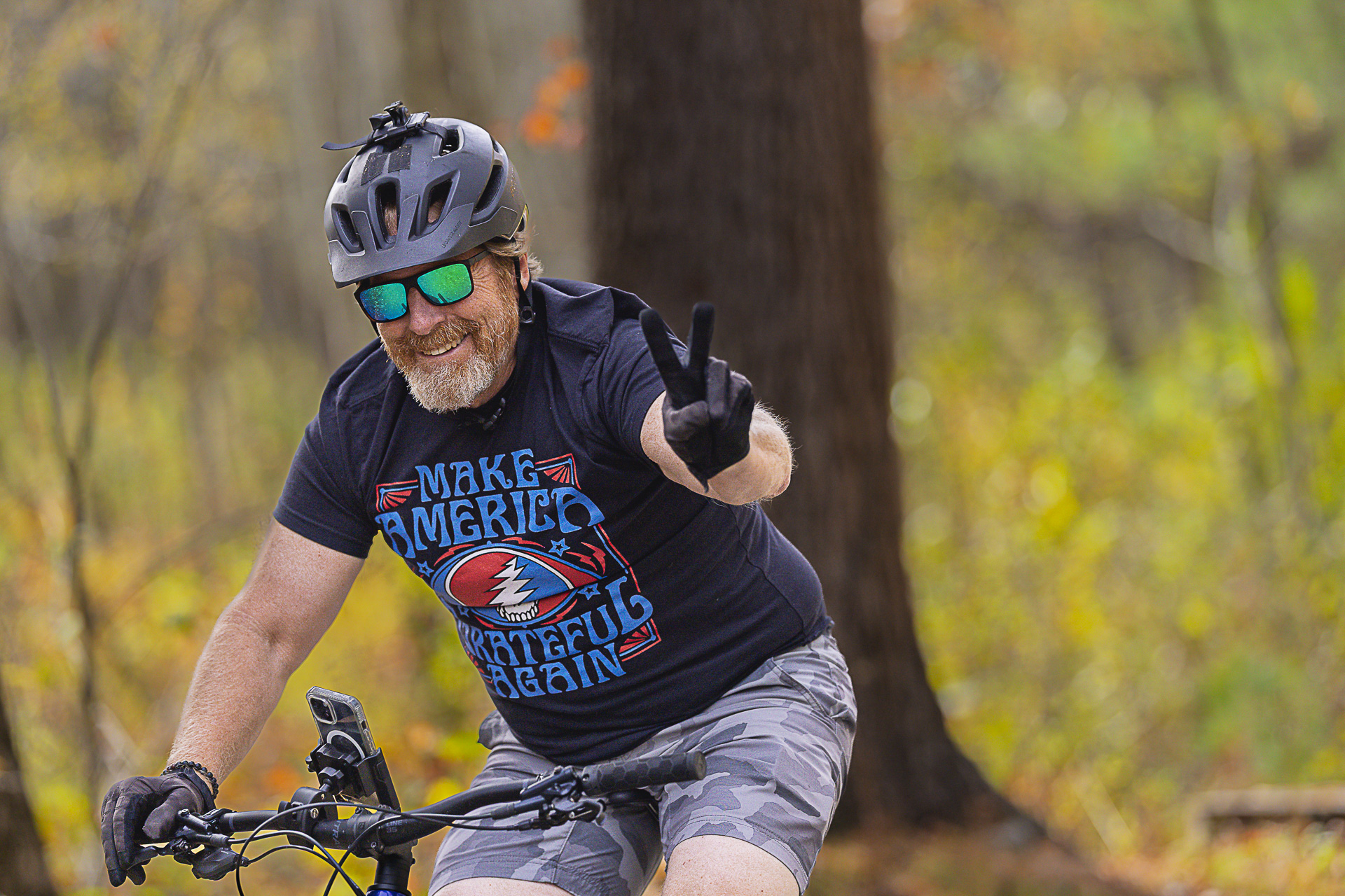 A smiling rider in sunglasses flashes a peace sign from the saddle