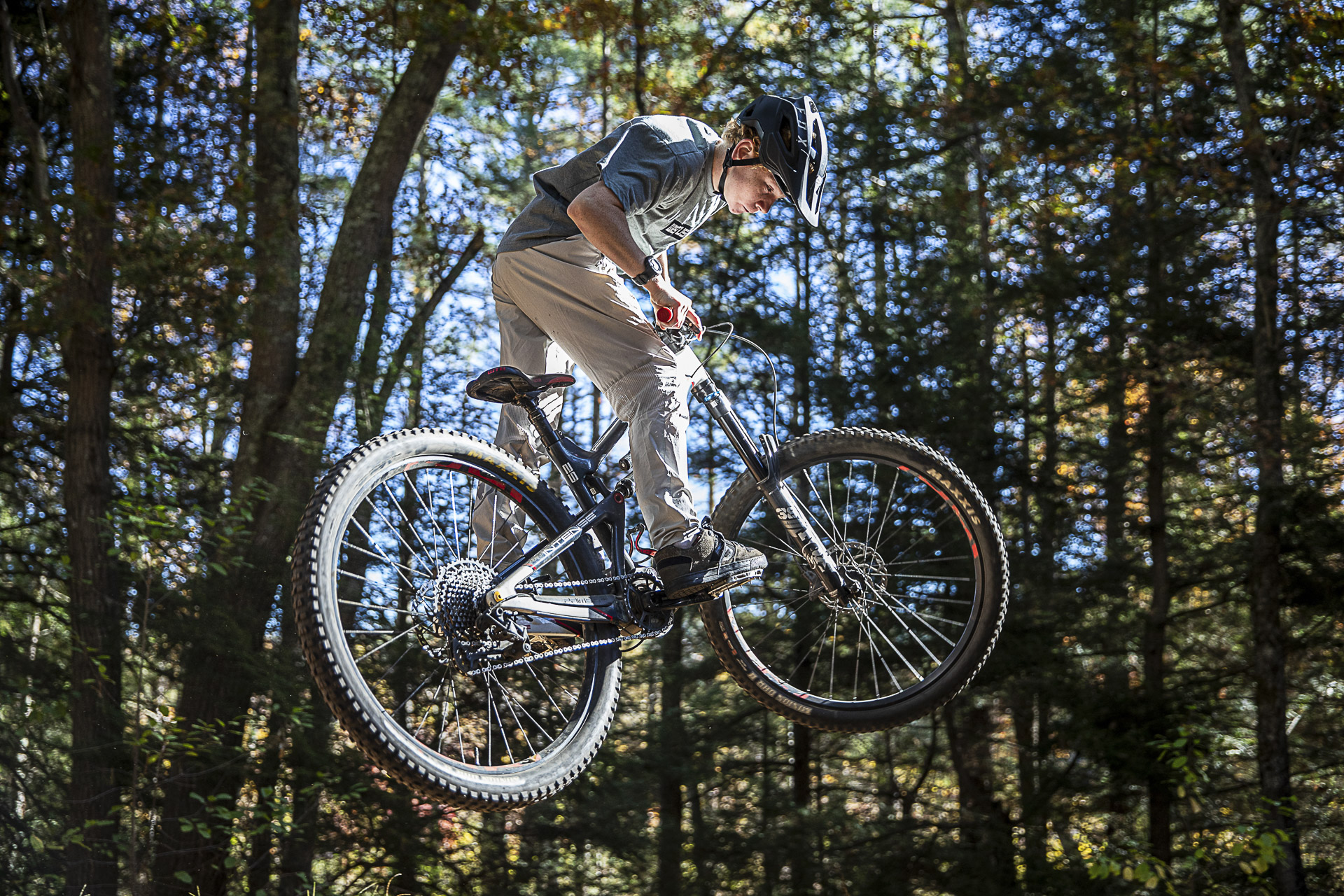 A young rider catches air against a backdrop of tall pines