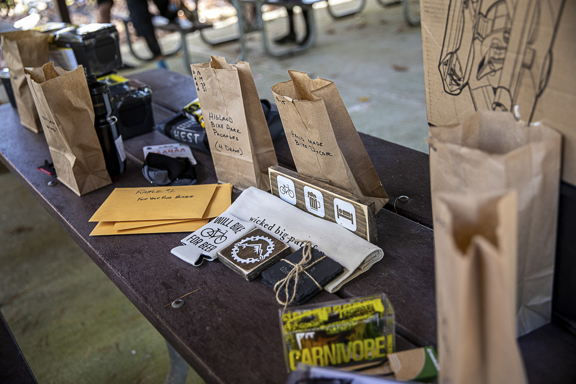 Raffle prizes in labeled paper bags on a picnic table